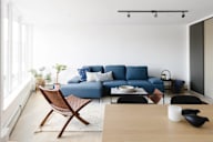 A blue couch sits in a living room with a wooden chair and coffee table.