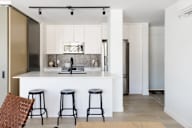 A kitchen with white cabinets and a bar area with stools.
