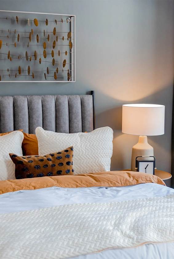 A bed with a white comforter and a pillow with a brown and black design.