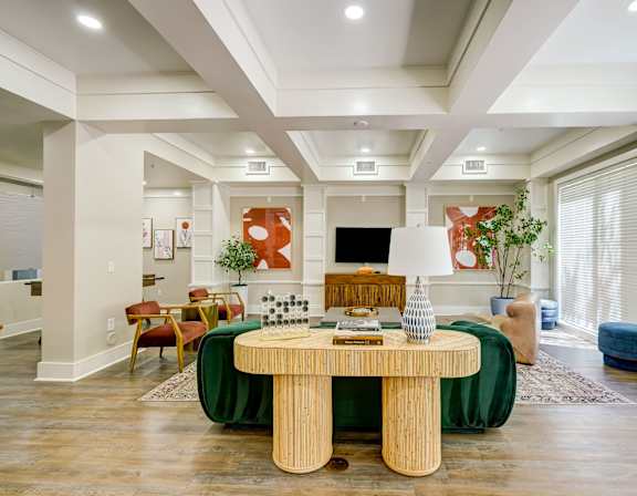 A living room with a green table and a TV on the wall.