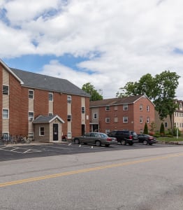 a large brick building with a gray roof and a parking lot in front of it