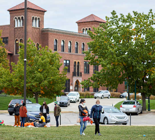people walking on the lawn in front of a large brick building