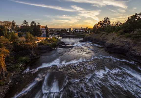 A river flows through a rocky landscape with a bridge in the background.