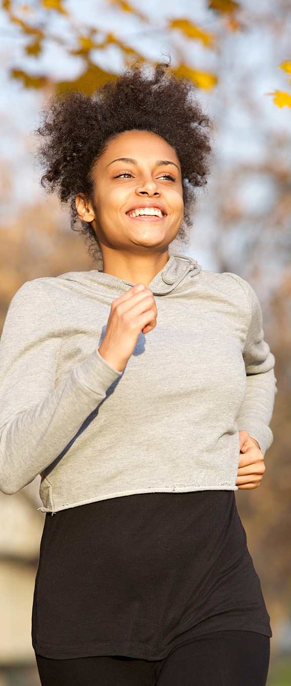 A woman with an afro hairstyle is running outdoors.