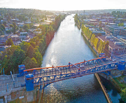 A bridge over a river with a city in the background.