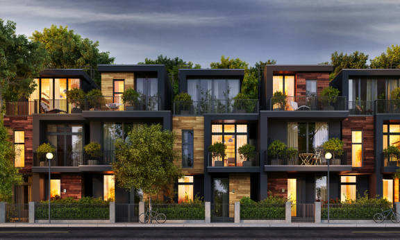 A modern apartment complex with balconies and trees in the foreground.