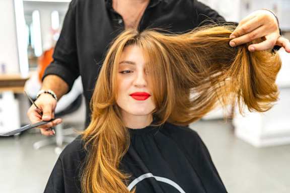 A hairdresser is cutting a woman's hair.