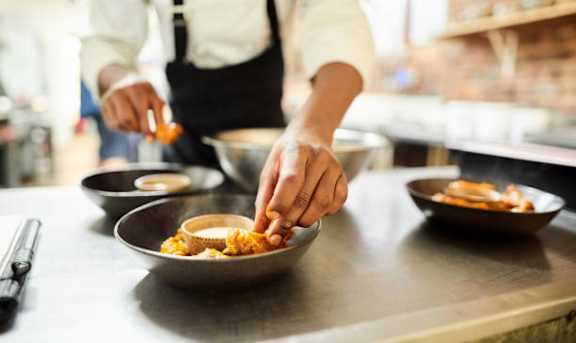 A chef is preparing food in a restaurant kitchen.
