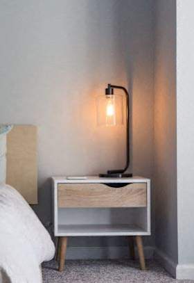 a bedroom with a bed and a nightstand with a lamp