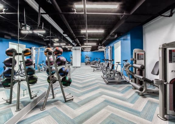 a workout room with cardio equipment and a chevron pattern on the floor