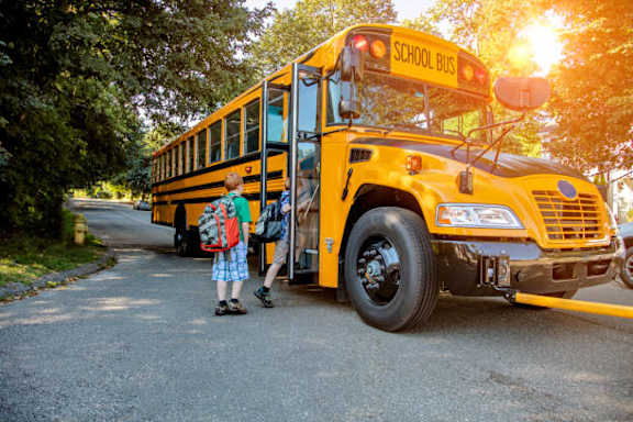 A child is getting off a yellow school bus.
