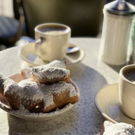 A cup of coffee and a plate of beignets on a table.
