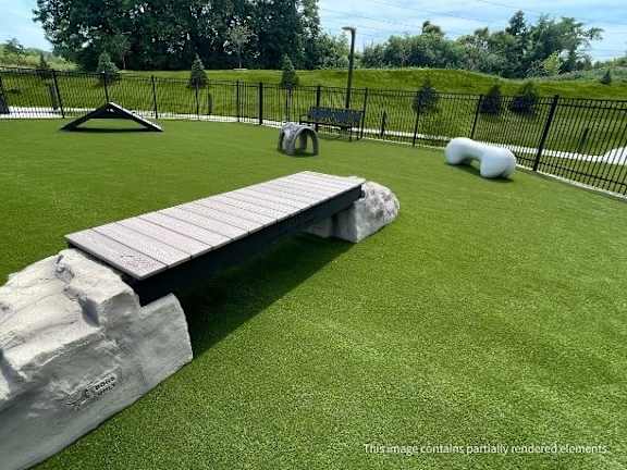 A playground with a slide, a rock, and a bench.