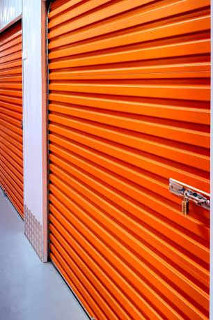 A long hallway with orange doors in a storage facility.