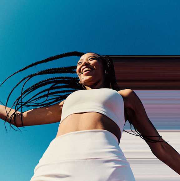 A woman with braided hair is wearing a white top and skirt.