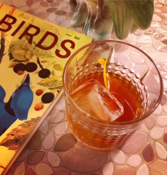 a cocktail in a glass on a table next to a book at Concourse, Memphis, 38104