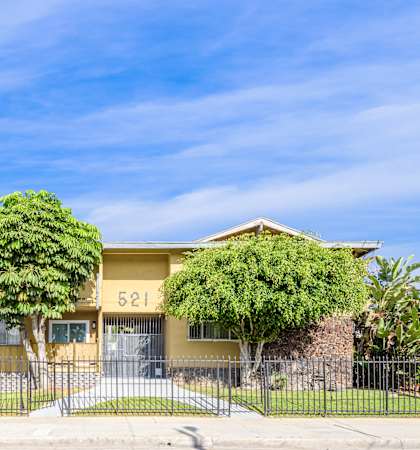 a yellow house with two trees in front of it