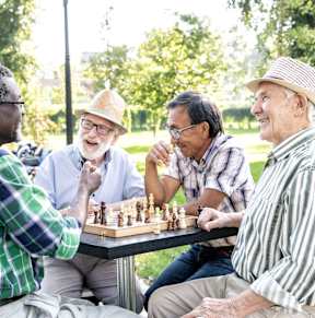 Four men playing chess in a park.