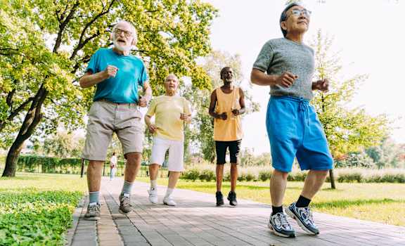 Four older men jogging in a park.