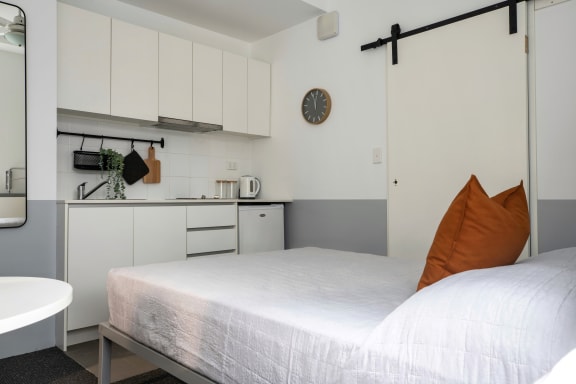 a small bedroom with a bed and a kitchen
