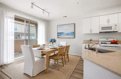 A modern kitchen with a dining table set for two.