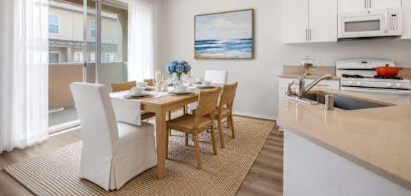 A modern kitchen with a dining table set for two.