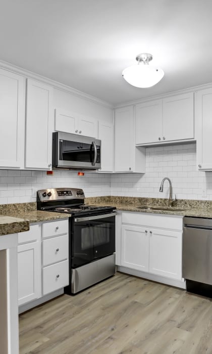 a kitchen with white cabinets and granite counter tops and stainless steel appliances