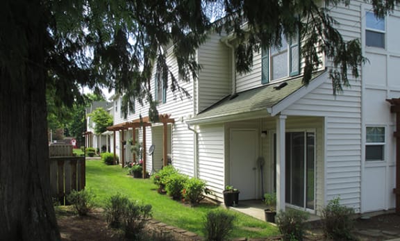 a row of white houses with grass and trees