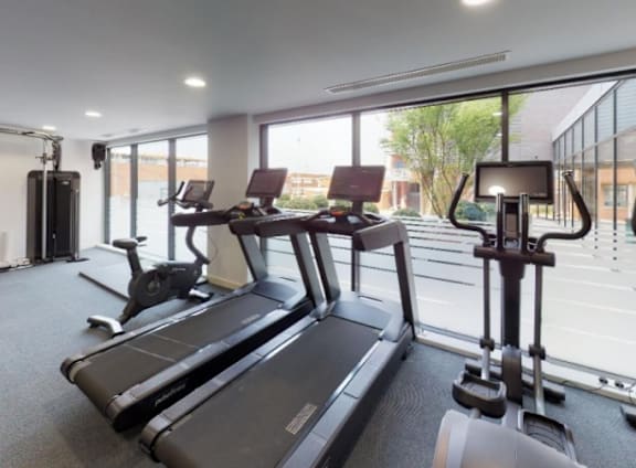 a gym with cardio machines and a large window at The Trilogy Apartments, Manchester, M15 4RU