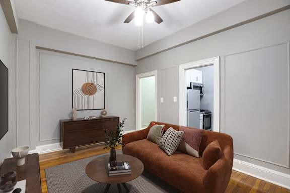 A living room with a brown couch and a ceiling fan.