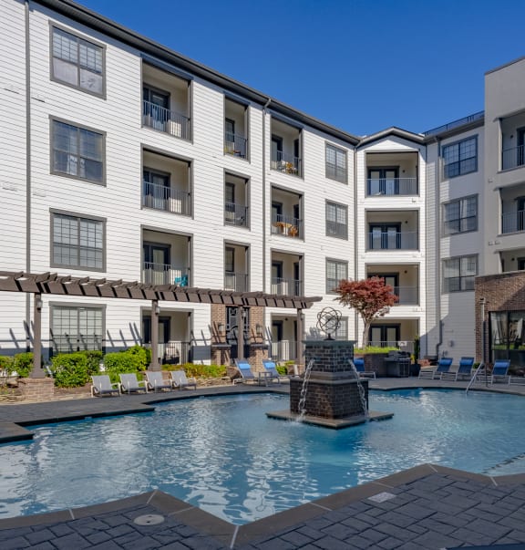 an outdoor pool with a fountain in front of a white building  at Bristol On Union Apartment Homes, Memphis, TN