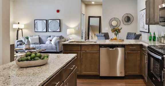 a kitchen and living room with a couch in the background and a bowl of fruit on the  at Aventura at Hawk Ridge, Lake St Louis