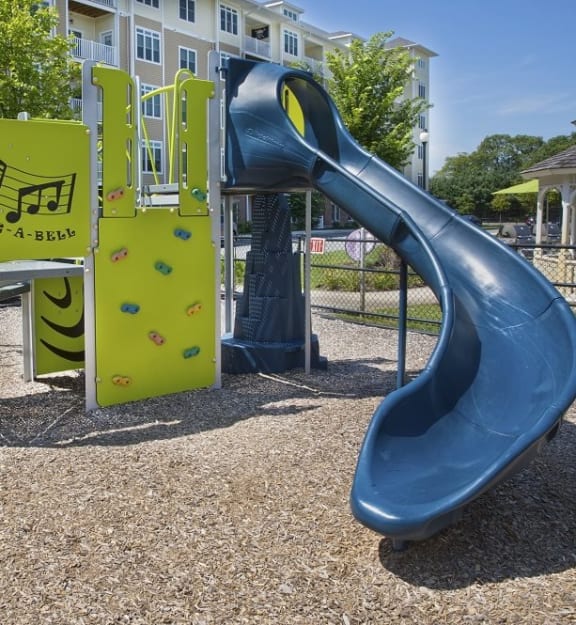 A playground with a blue slide and a yellow wall with a musical note on it at Axis at Lakeshore Apartments, Bridgewater, MA 02324