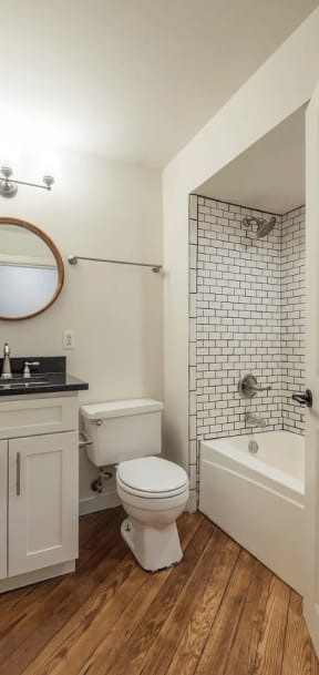 a bathroom with white walls and a wooden floor