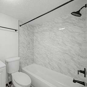A white bathroom with a toilet, sink, and bathtub.
