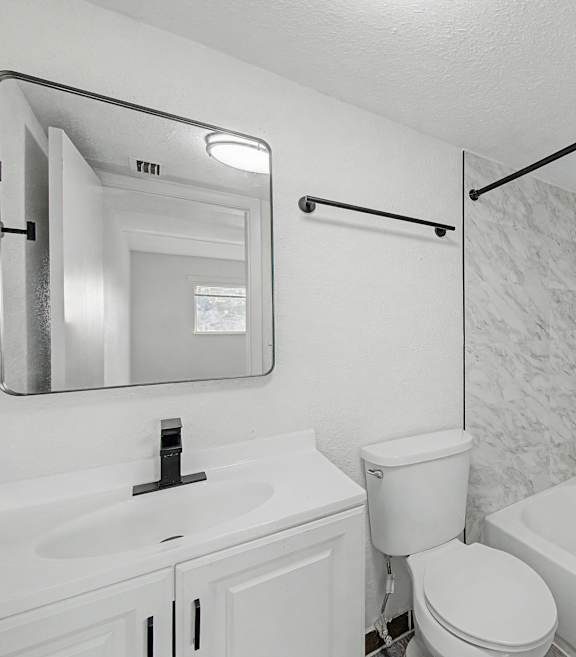 A white bathroom with a toilet, sink, and bathtub.