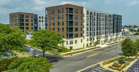 A large apartment complex with multiple buildings and a parking lot in front.