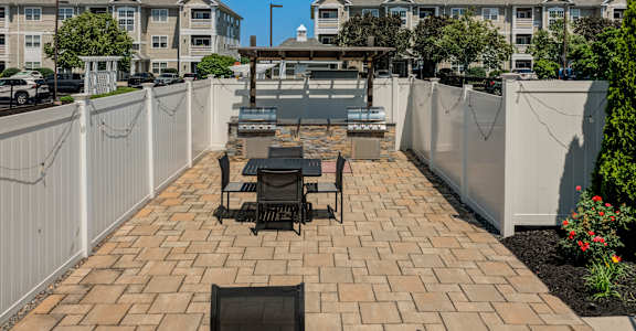 A patio with a table and chairs is surrounded by a white fence.