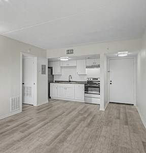 A kitchen with white cabinets and a wooden floor.