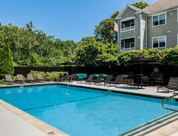 A large swimming pool with lounge chairs and a building in the background.