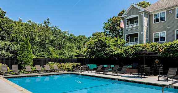 A large swimming pool with lounge chairs and a building in the background.