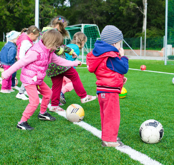 a group of young children kicking soccer balls on a field