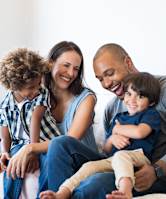 A family of four is sitting on a couch together.