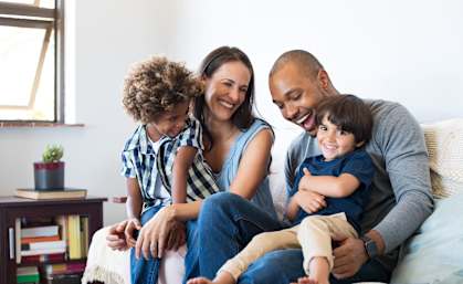 A family of four is sitting on a couch together.
