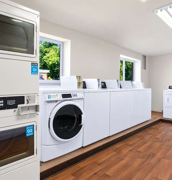 A row of white appliances in a room with wooden floors.