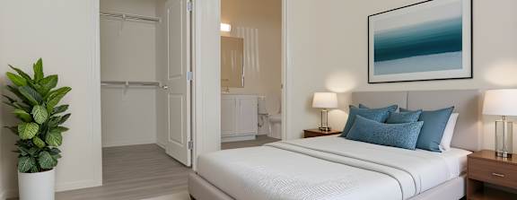 A bedroom with a large bed and a potted plant.