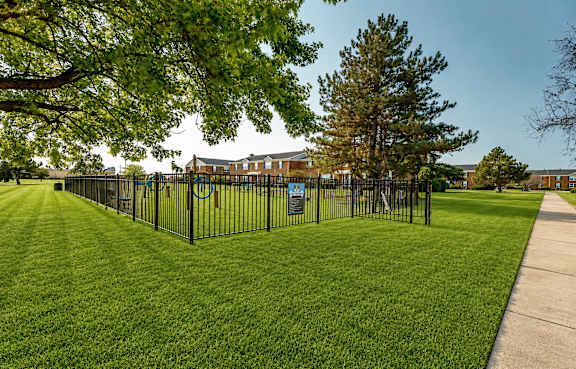 Fenced dog park with green lawn at Canterbury Square Apartments, Troy