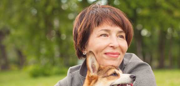 a woman holding a dog in a park