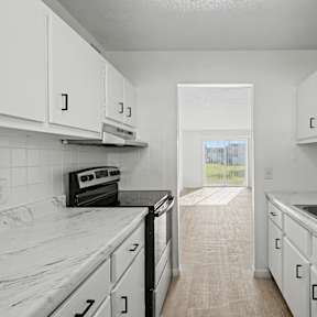A kitchen with white cabinets and marble countertops.