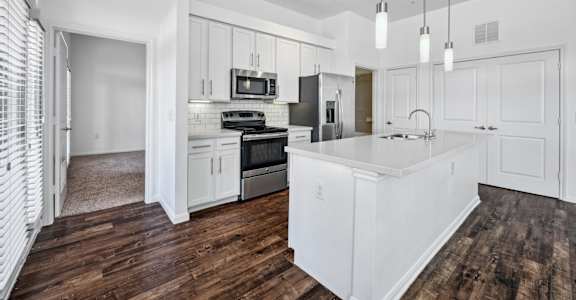 an open kitchen with white cabinets and a large white island at Radius on Grove, Austin